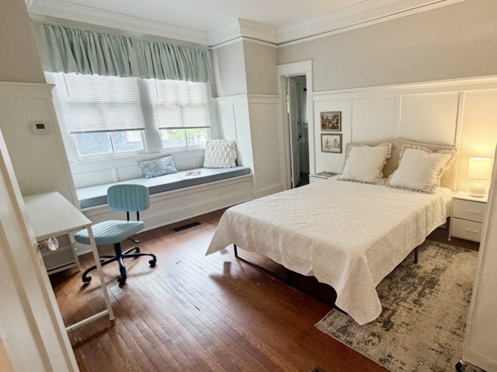 Primary bedroom with a large window seat and painted wainscoting