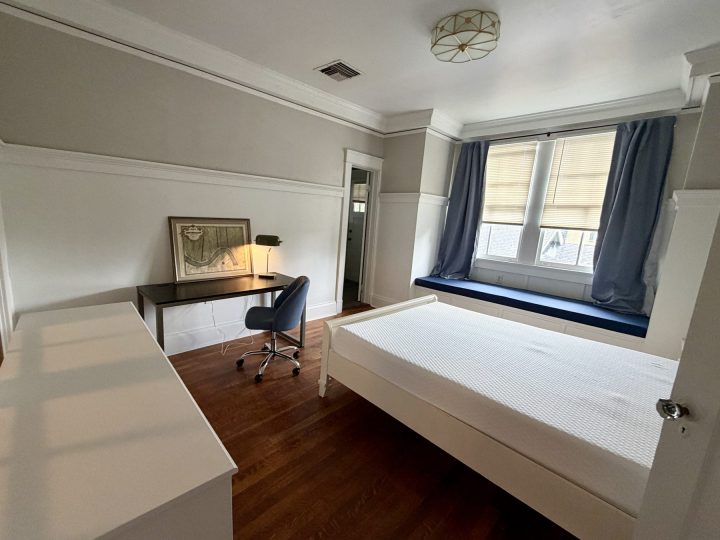 Bedroom with a desk, window seat and navy curtains