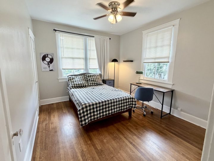 Bedroom with a checked bedspread, desk and paired windows